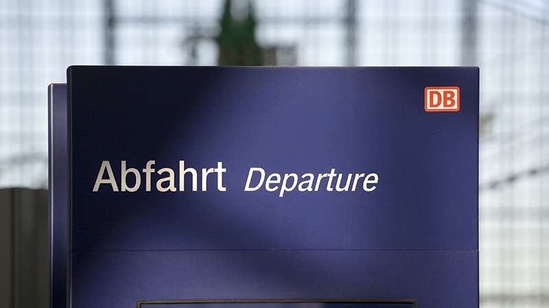 Auf dem Bild ist eine Tafel mit dem Word 'Abfahrt' und dem Logo der Deutschen Bahn zu sehen.